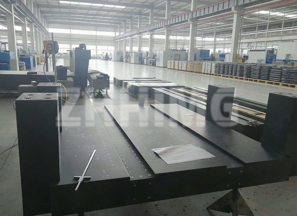 Large gantry-style precision granite machine base with multiple columns and tapped inserts in the workshop